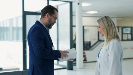 Pharmaceutical sales representative talking with doctor in medical building. Ambitious male sales representative presenting new medication on tablet.