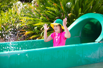 Kids on water slide in aqua park. Summer vacation