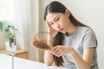 Stress asian young woman, girl hand holding comb show her hairbrush with loss, hair in brush after...