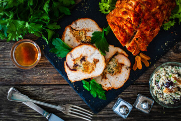 Stuffed turkey breast roulade with dried apricots and cranberries on wooden table
