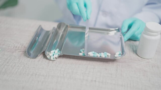A female pharmacist's hand demonstrates how to count white pills in a pill counting tray. Health care concept.