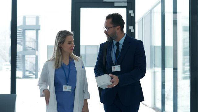 Pharmaceutical sales representative talking with doctor in medical building. Ambitious male sales representative presenting new medication.