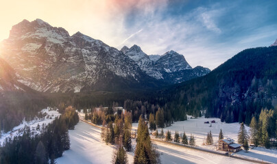 Winter Sunset Over Snow-Covered Peaks at Auronzo Di Cadore, Italy. A breathtaking winter scene unfolds as the warm glow of the setting sun kisses the snowy Dolomites peaks and tranquil forests 