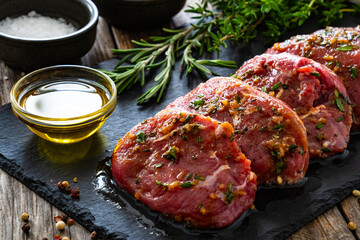 Raw pickled pork cheeks on stony cutting board on wooden table
