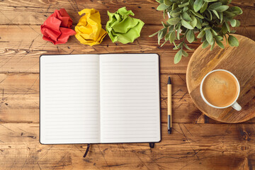Notebook mock up with coffee cup and plant on wooden office desk. Top view, flat lay