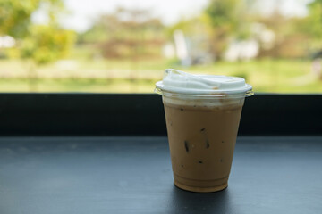 Ice cappuccino coffee on table with spring garden view of outdoor cafe