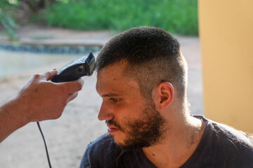 military haircut, young man cutting his hair with an electric machine