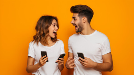 Fototapeta premium young man and woman are both holding smartphones and smiling at each other, with a bright orange background