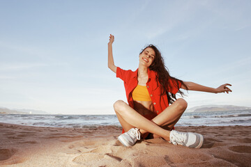 Fototapeta na wymiar Happy Woman Sitting on a Beautiful Beach, Enjoying a Trendy Summer Vacation, Smiling with Joy and Happiness, Feeling the Sand Between Her Toes, Embracing the Wide Angle View of the Serene Sea and