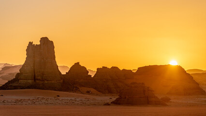 Landscape of the Red Tadrart in the Sahara Desert, Algeria. Sunset behind wind-sculpted sandstone...
