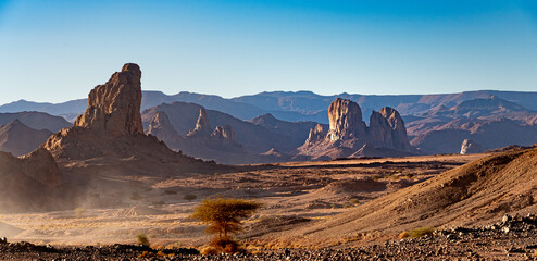 Hoggar landscape in the Sahara desert, Algeria. Steep peaks rise up in a mineral setting - 732663152