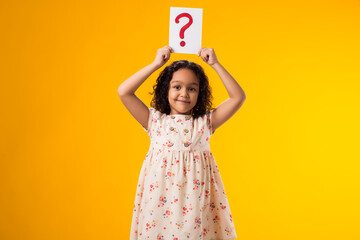 Smiling kid girl holding question mark card. Children, idea and knowledge concept
