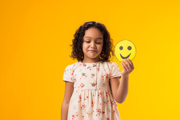 Kid girl holding happy emoticons. Mental health, psychology and children's emotions concept