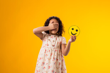 Kid girl holding happy emoticons and covering face with hand. Mental health, psychology and...