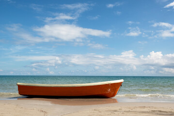 View of beach on sunny day with orange boat in the foreground