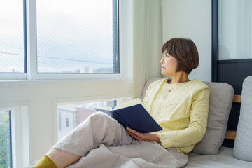 窓辺で空を眺める女性