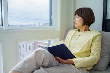 窓辺で外を眺めるシニア女性