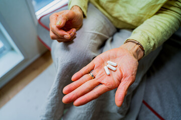 手のひらに薬をだすシニア女性