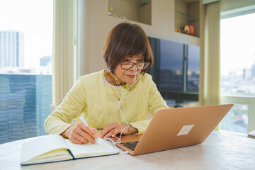 ノートパソコンで勉強するシニア女性