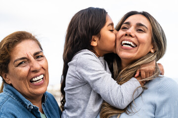 Happy Hispanic family enjoying time together - Child having fun with her mother and grandmother outdoor
