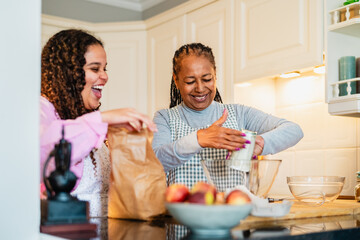 Happy African mother and daughter having fun preparing a homemade dessert