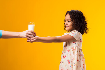 Smiling child girl taking fron hands glass of milk. Nutrition and health concept