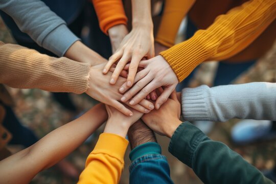 A close-up of a diverse group of people stacking their hands together in a show of unity and teamwork. concept of unity in diversity.