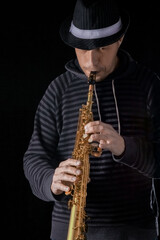 soprano saxophone in the hands of a guy on a black background
