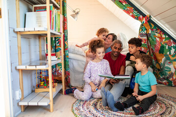 Young family reading a book together in the bedroom