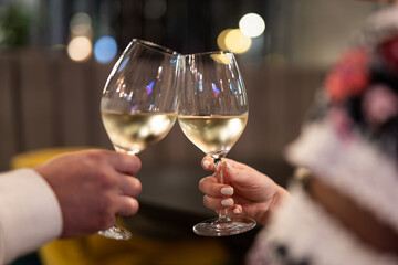 two people are holding glasses with an alcoholic drink