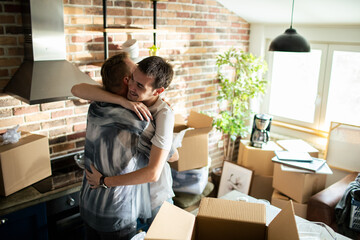 Young male gay couple hugging after moving in - obrazy, fototapety, plakaty
