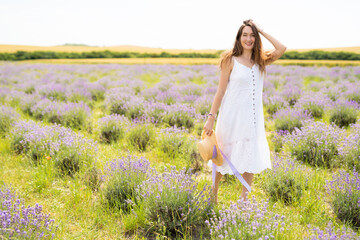 beautiful girl in a dress with a straw hat on a lavender field