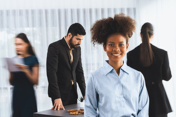 Young African businesswoman portrait poses confidently with diverse coworkers in busy meeting room...