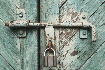 old metal lock on a wooden door with cracked paint