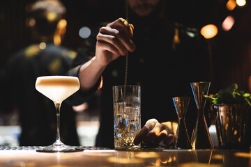 the bartender prepares a beautiful alcoholic cocktail at the bar counter