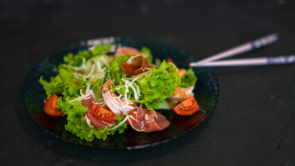 Seafood salad served on a beautiful plate. Salad with king prawns and prosciutto.