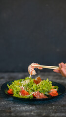 Seafood salad served on a beautiful plate. Salad with king prawns and prosciutto.