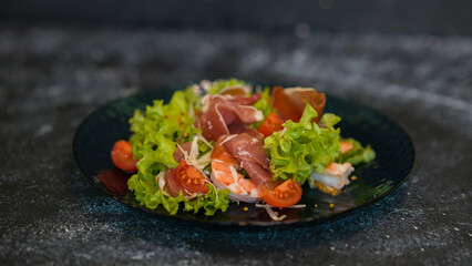 Seafood salad served on a beautiful plate. Salad with king prawns and prosciutto.
