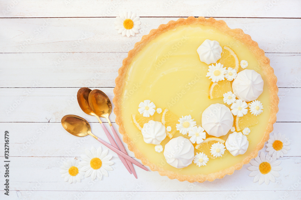Aufkleber spring lemon tart with white chocolate flowers and meringue. top view table scene over a white wood 