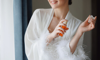 Closeup young woman with makeup use perfume, radiant bride smiling. Concept morning and getting...
