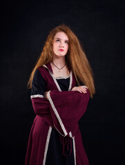 Red-haired girl in a vintage burgundy dress on a black background.