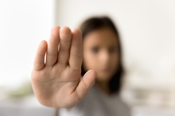 Scared kid making hand stop gesture, showing palm at camera, symbol of warning, restriction,...