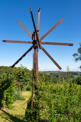 Scenic view of vineyards and windmill klapotetz in Ehrenhausen an der Weinstrasse, Leibnitz, South Styria, Austria. Idyllic winery stretching over lush green hills. Panorama in Styrian Tuscany