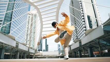 Stylish asian man perform hiphop dancing with low angle camera. Break dancer walking up the stair while listening music from headphone and dancing together at city. Outdoor sport 2024. Sprightly. - obrazy, fototapety, plakaty