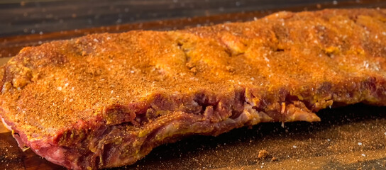 Beef ribs meat part with spices on wood background. Homemade cooking beef for restaurant, menu, advert or package, close up, selective focus