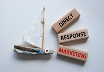 Direct Response Marketing symbol. Concept words Direct Response Marketing on wooden blocks. Beautiful white background with boat. Business and Direct Response Marketing concept. Copy space.