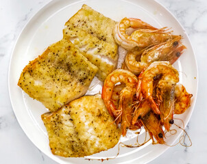 Fried fish fillet steak with shrimps, salt pepper on plate. Homemade cooking fish sliced for restaurant, menu, advert or package, close up, selective focus