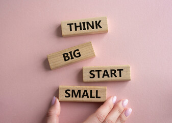 Think big start small symbol. Concept words Think big start small on wooden blocks. Beautiful pink background. Businessman hand. Business and Think big start small concept. Copy space