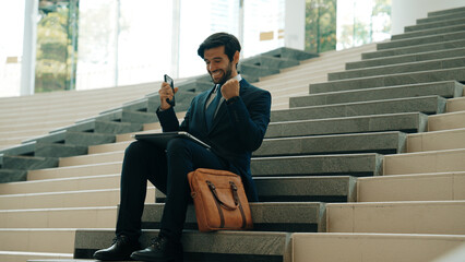 Successful business man celebrate successful project while sitting at stairs. Smart project manager...