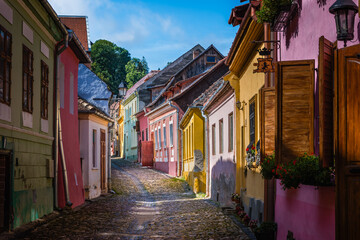 Uphill view on empty Sighisoara street with colorful medieval houses, Romania